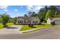 Charming single-story home featuring a well-manicured lawn, mature landscaping, and a welcoming front porch at 1505 Bramber Pl., Conway, SC 29527