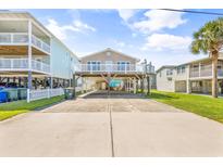 Inviting raised beach house with covered parking, white railings, and a glimpse of the beautiful sky at 209 25Th Ave. N, North Myrtle Beach, SC 29582
