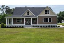 Charming home featuring an inviting front porch and lush green lawn with manicured landscaping at 214 Carolina Dr., Loris, SC 29569