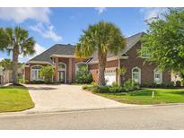 Beautiful brick home featuring lush landscaping, palm trees, and a brick driveway at 220 Waterfall Circle, Little River, SC 29566