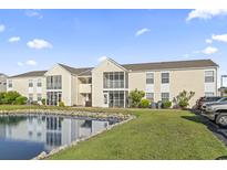 A condo exterior featuring a pond, beige siding, screened-in porches, and neatly kept lawns and shrubs at 2258 Essex Dr. # G, Surfside Beach, SC 29575