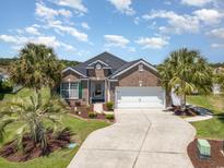 Charming brick home with a two-car garage, manicured landscaping, and palm trees at 2940 Tigers Eye Rd., Little River, SC 29566