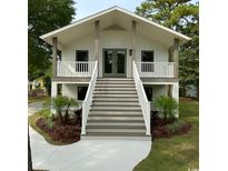 Charming two-story home featuring a lovely stairway, elevated porch, and beautifully landscaped front yard at 326 15Th Ave. S, Surfside Beach, SC 29575
