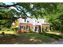 Charming brick home features a manicured front lawn and inviting entrance with white columns and a balcony above at 402 E Broad St., Hemingway, SC 29554