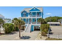 Charming blue beach house with double balconies and white stairs, surrounded by lush landscaping at 4206 S Ocean Blvd., North Myrtle Beach, SC 29582