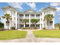Three-story condo building with white siding, multiple balconies, and beautiful landscaping with palm trees at 665 Tupelo Ln. # 17-F, Longs, SC 29568
