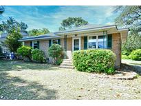 Charming single-story brick home featuring a cozy front porch and lush landscaping at 703 S 21St Ave. S, North Myrtle Beach, SC 29582