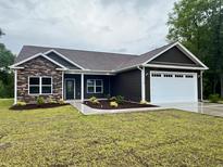 New construction home features a stone facade, dark siding, manicured landscaping, and attached two car garage at 718 Highway 348, Loris, SC 29569