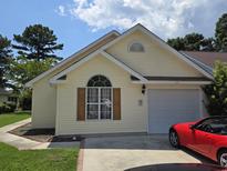Charming one-story home with a well-maintained lawn and attached garage and red sports car at 117 Wagon Wheel Ln., Surfside Beach, SC 29575