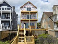New beach home is shown under construction with decks and stairs leading to the ground at 1611A S Ocean Blvd., Surfside Beach, SC 29575