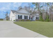 Charming white home featuring a well-manicured lawn, a concrete driveway, and classic black shutters at 250 Ole Maple St., Loris, SC 29569
