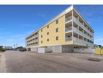 Beautiful exterior shot of a yellow condo building with large balconies under a bright blue sky at 301 N Waccamaw Dr. # 110, Murrells Inlet, SC 29576