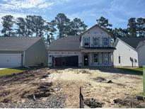 New construction home with a two-car garage surrounded by dirt and other homes in the distance at 402 Sun Colony Blvd., Longs, SC 29568