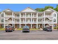 Three-story condo building with white balconies, green shutters, and well-maintained landscaping at 4429 Turtle Ln. # 3A, Little River, SC 29566
