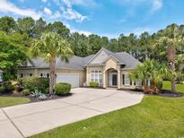 Charming single-Gathering home showcasing mature landscaping and a long driveway and attached garage at 5916 Falcon Landing Circle, North Myrtle Beach, SC 29582