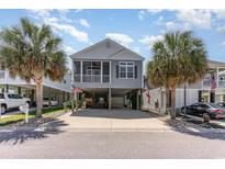 Charming coastal home featuring a screened porch, neutral siding, palm trees, and ample parking beneath at 708 Ashland Ave., North Myrtle Beach, SC 29582