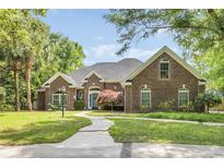 Charming brick home featuring a lush, landscaped yard and inviting walkway at 1203 Crooked Oak Dr., Pawleys Island, SC 29585