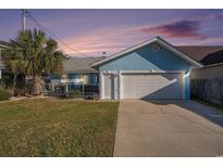 Charming blue house featuring an attached garage, green lawn, and palm tree at 1415 Edge Dr., North Myrtle Beach, SC 29582