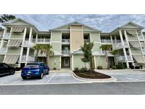 Inviting exterior view of a charming two-story condo building with palm trees and well-maintained landscaping at 144 Puffin Dr. # 1-A, Pawleys Island, SC 29585