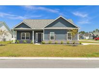 Charming single-story home with blue siding, brick foundation, lush lawn, and professionally landscaped front yard at 383 Hayloft Circle, Conway, SC 29526