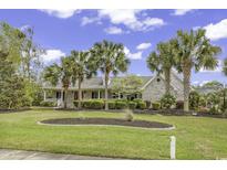 Charming single-story home with white brick, lush landscaping, palm trees, and inviting front porch at 552 Enoree Ct., Myrtle Beach, SC 29588