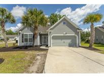 Charming single-story home featuring a manicured front yard, attached garage, and classic gray siding at 601 Blue Daisy Ct., Loris, SC 29569