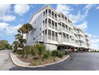 Coastal condo building featuring multiple balconies, palm trees, and covered parking at 9581 Shore Dr. # 216, Myrtle Beach, SC 29572