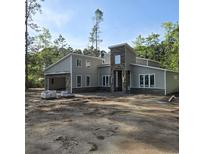 Modern home with light beige siding, stone accents, and a two-car garage nestled among mature trees at 1028 Colette Ct, Conway, SC 29526