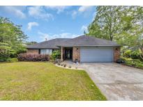 Charming brick home boasts a manicured lawn, mature trees, and an attached two-car garage at 215 Lander Dr., Conway, SC 29526