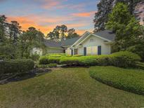 Charming single-story home surrounded by lush greenery and trees beneath a vibrant, colorful sunset at 28 Torrens Pl., Pawleys Island, SC 29585