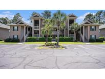 Exterior view of the condo building featuring parking and well-manicured landscaping at 342 Pinehurst Ln. # 12J, Pawleys Island, SC 29585