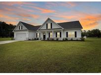 Charming home features a well-manicured lawn, black shutters, and an attached garage in a suburban neighborhood at 40 Little Peru Ct., Georgetown, SC 29440