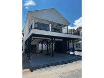 A beautiful white elevated two-story home with a black iron balcony, sturdy stilts, and ample covered parking at 6001 - 1766 S Kings Hwy., Myrtle Beach, SC 29575
