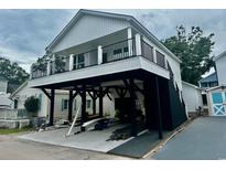 Two-story home with white siding, black trim, elevated design and a covered parking area beneath the house at 6001 - 1766 S Kings Hwy., Myrtle Beach, SC 29575