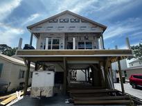 Under-construction stilt home with wood framing, unfinished exterior, and a partially completed deck at 6001 - 1766 S Kings Hwy., Myrtle Beach, SC 29575