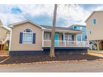 Charming beach house featuring a spacious porch with white railings and a bright teal front door at 6001-8026 South Kings Hwy., Myrtle Beach, SC 29575