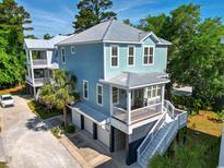 Beautiful two-story blue home featuring an inviting front porch, metal roof, and convenient garage parking at 18 Coastal Breeze Trail, Pawleys Island, SC 29585