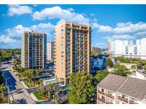 An aerial view showcasing the condo complex, featuring palm trees, a pool, and nearby roads on a sunny day at 210 75Th Ave N # 4042, Myrtle Beach, SC 29572