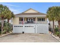 Charming beach house with a covered balcony, palm trees, and white garage doors at 337 59Th Ave. N, North Myrtle Beach, SC 29582