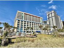 Large modern condo building featuring multiple balconies with palm trees and playground at 5300 N Ocean Blvd. # 1102, Myrtle Beach, SC 29577