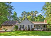 Charming single-story home with a well-manicured lawn and a detached two-car garage, set amongst mature trees at 57 River Birch Ln., Pawleys Island, SC 29585