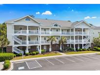 Three-story condo building with white railings, palm trees, and a parking lot at 6015 Catalina Dr. # 332, North Myrtle Beach, SC 29582