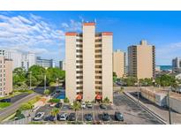 High-rise condo building showing parking, pool, and landscaping on a bright, sunny day at 7509 N Ocean Blvd. # 404, Myrtle Beach, SC 29572