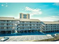 Condos with covered parking beneath and an ocean-view high-rise in the background on a sunny day at 9621 Shore Dr. # F-117, Myrtle Beach, SC 29572