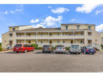 Multi-level condo building with yellow exterior and multiple cars parked in front on a sunny day at 1100 Possum Trot Rd. # D-205, North Myrtle Beach, SC 29582
