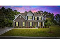 Charming two-story home featuring a brick facade, complemented by lush landscaping, and a welcoming blue front door at 1303 Bermuda Grass Dr., Myrtle Beach, SC 29579