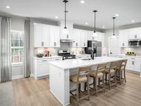 Modern kitchen featuring white cabinetry, stainless steel appliances, and a spacious island with barstool seating at 1312 Piper Glen Dr, Sunset Beach, NC 28468