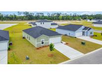 A new construction home with an attached garage and a well-manicured lawn in a suburban neighborhood at 1372 Palm Springs Paloma Dr, Longs, SC 29568