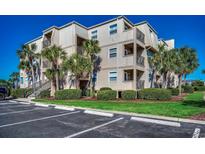 Three-story condo complex with balconies, palm trees and manicured landscaping at 1582 S Waccamaw Dr. # 34, Garden City Beach, SC 29576