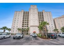 Condo building's exterior with a parking area, palm trees, and a blue sky backdrop at 2151 Bridge Ct. # 1-305, North Myrtle Beach, SC 29582